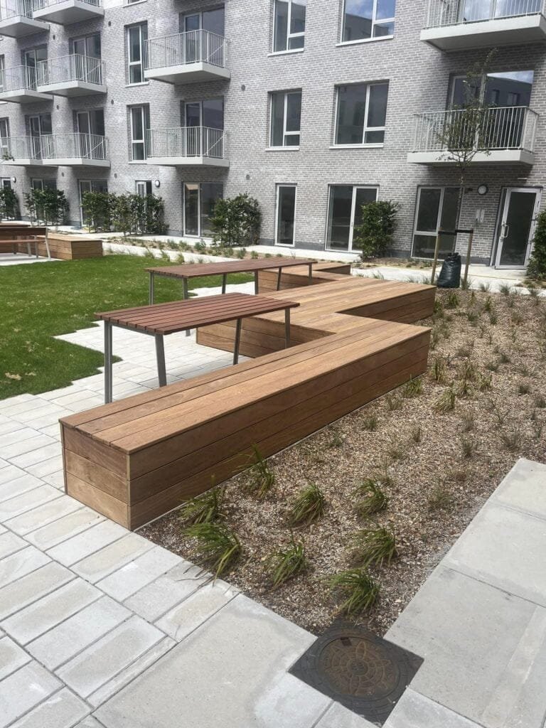 Moderne gårdhave med træbænke og lejlighedsbygning
