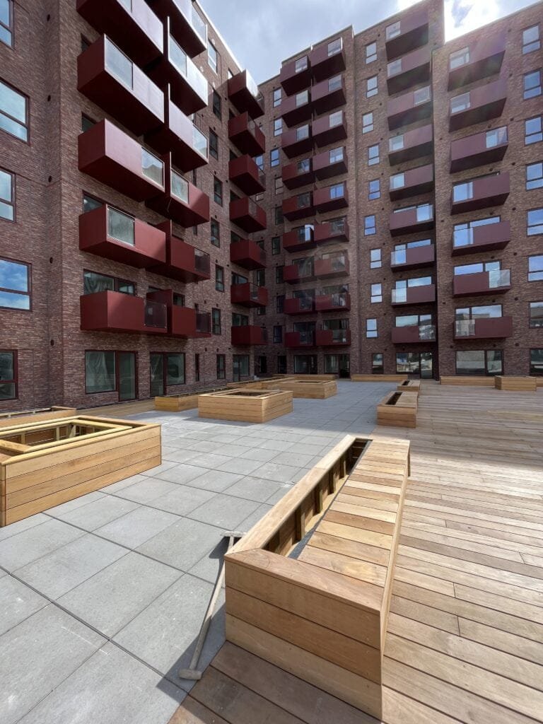 Moderne lejlighedsbygning med røde altaner og gårdhave