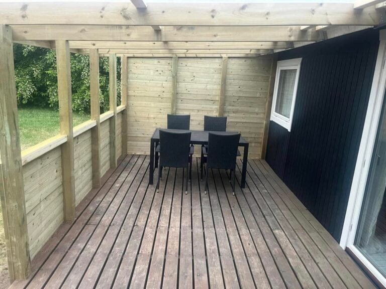 Træterrasse med sort bord og fire stole