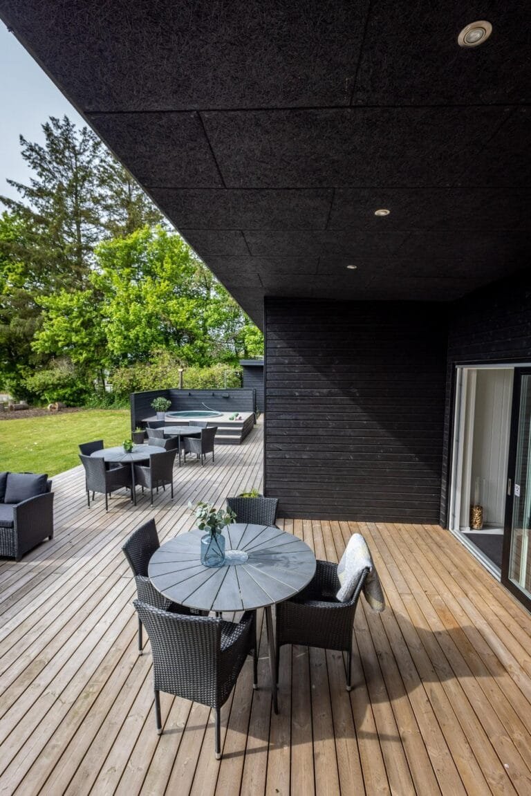 Overdækket træterrasse ved sort træbeklædt sommerhus